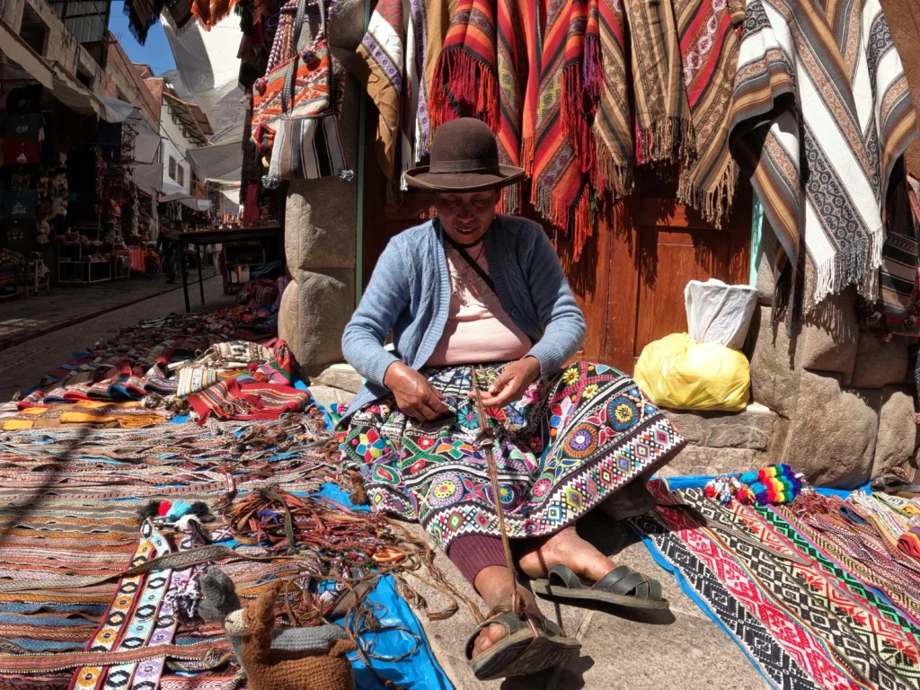 Tejedora quechua en mercado de San Pedro, Cusco, preservando tradiciones ancestrales